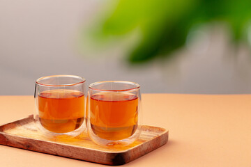 Two glass cups of black tea on beige table
