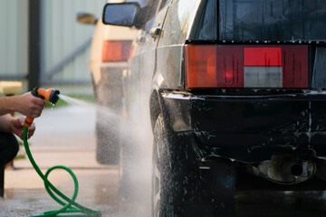 
water from a hose with a sprayer washes the car