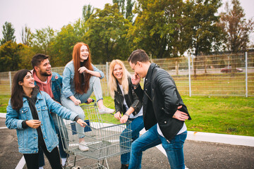 Fototapeta premium Unstoppable. Group of four young diverse friends in jeanse outfit look carefree, young and happy walking down the city's streets. Fashion of urban clothes, freedom, friendship, style concept.