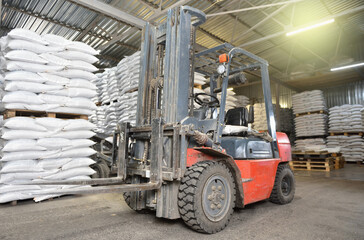 Fototapeta na wymiar A forklift stands in a warehouse next to pallets with full bags