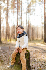 little preschool boy in casual clothes walks through the spring forest in the evening, backlight