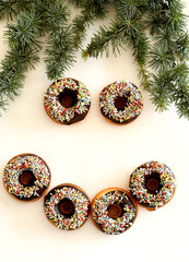 Delicious chocolate donuts isolated on a white background.  Christmas tree branches background. Happy smiley.