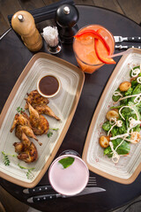 Grilled quail and seafood salad with cocktails on round table at restaurant