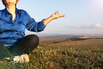 Portrait of an elderly woman doing yoga in nature.