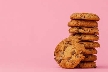 Stacked chocolate chip cookies against pink background