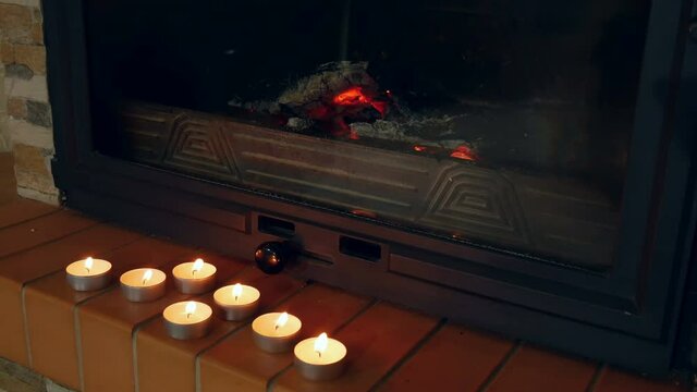 Advent candles near fireplace burning in shallow focus in darkness. Candles on mantel of fireplace as romantic background