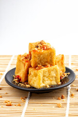 Fried tofu is stacked and sprinkled with peanuts and sweet sauce on black plate, food of vegetarian, popular food of vegetarian festival.