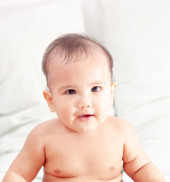 Cute Baby sitting On the bed and looking at the camera