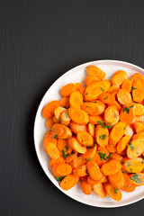 Homemade Sauteed Carrots on a plate on a black background, top view. Flat lay, overhead, from above.