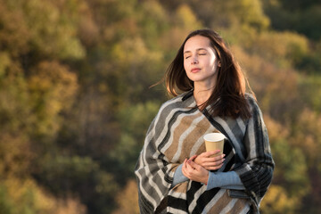 Beautiful girl on nature background of dreams. Travel in the fall. Coffee in hand.