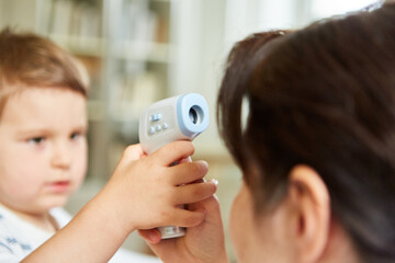 Kind und Kinderärztin üben Fieber messen