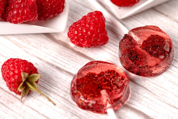 Homemade lollipops made from natural dehydrated strawberries and raspberries on a white wooden background. Healthy vegan vegetarian food with no sweets.