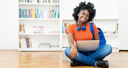 Laughing african american female student learning online at computer with other students