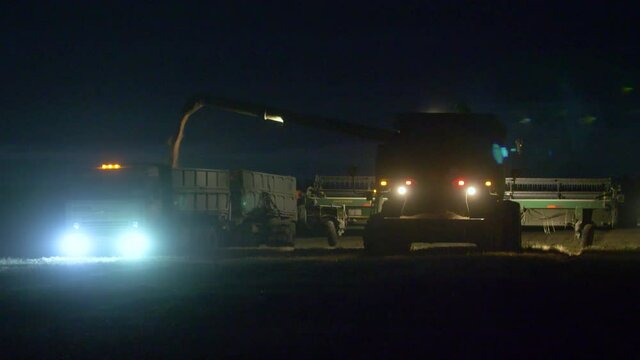 The combine harvester works at night in the field lighting its way with lanterns