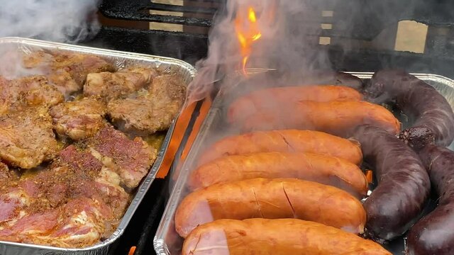 Marinated pieces of meat and german sausages grilled on bbq grill at the yard in Poland daytime