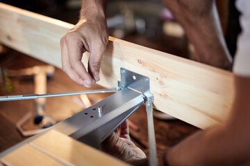 Carpenter hobbyist assembling wooden boards at home / garage.