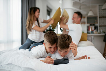 Two little brothers are playing games on the phone. Beautiful boys enjoying at home..