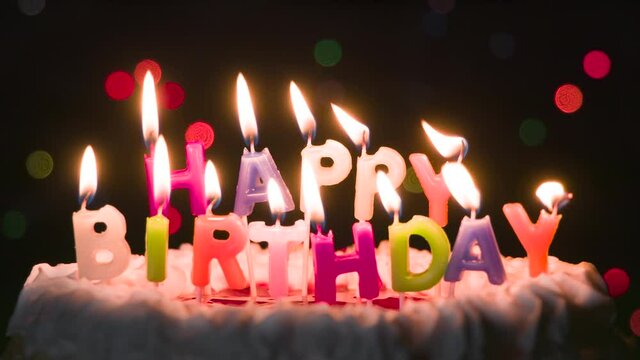 Candles are Blown Out on the Birthday Cake. Cake with candles in the form of an inscription Happy Birthday. The candles in slow mo are slowly extinguished by blowing out
