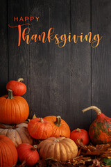 Thanksgiving Greetings. Pumpkins and dry leaves on a dark wooden background.