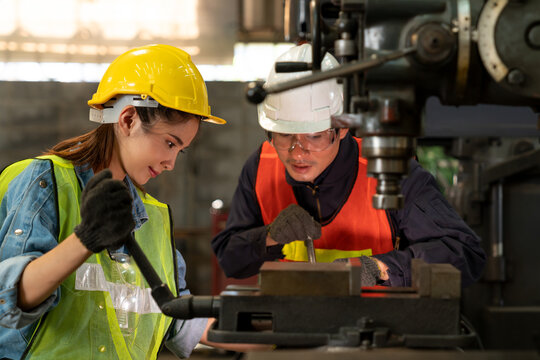 Focus on confident female worker wearing hard hat working with a man in industrial. Technician engineer control machines in the factory on business day. Concept of workplace gender equality
