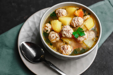 A bowl of soup with meatballs and potatoes. Light rustic soup. top view, horizontal shot