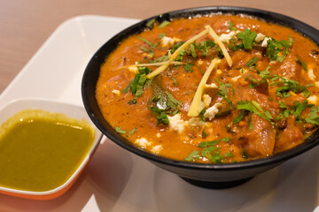 traditional Indian food, stewed vegetables with curry and paneer cheese, coriander sour sauce, food for vegans and vegetarians, garnished with grated ginger and cilantro leaves