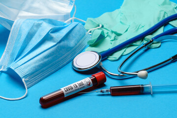 Top view of Medical equipment and tools on blue background - stethoscope, surgical mask, medical gloves, syringe and test tube - healthcare and medicine concept