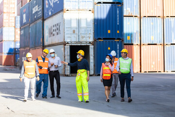 Group of professional team worker walking to working and wearing protection face mask during coronavirus and flu outbreak and wearing safety hardhat helmet at container yard or cargo warehouse