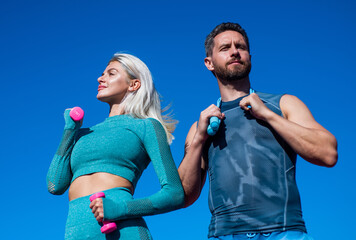 sport couple in sportswear training with barbells and skipping rope on sky background, fitness