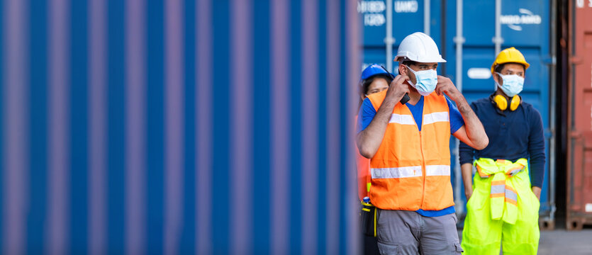 Group of professional team worker walking to working and wearing protection face mask during coronavirus and flu outbreak and wearing safety hardhat helmet at container yard or cargo warehouse