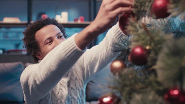 happy african american man decorating christmas tree