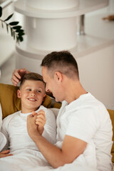 Father and son enjoying in bed. Happy man with son relaxing in bed.