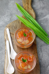 Es Buah, Indonesian traditional cocktail fruits popular during Ramadan month, made from sugar syrup, papaya, pineapple and other fruits. Served on clear glass on, grey wooden background. Copy space.