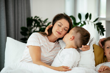 Fototapeta na wymiar Mother and son enjoying in bed. Happy woman with son relaxing in bed.