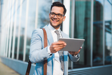 Smiling attractive manager holding tablet in the street