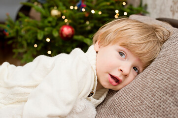 boy in white warm winter sweater with white Teddy bear in Christmas tree background. happy wide smile