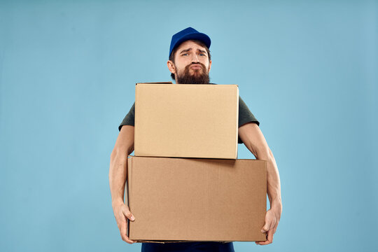 Man in working uniform with boxes in hands delivery service blue background