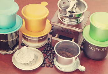 Traditional vietnamese drip coffee, coffee phin, coffee grinder and beans on wooden table