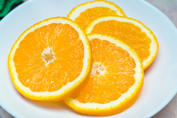 A few fresh slices of orange on a white plate. Top view, close up image