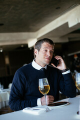 Handsome businessman dressed in the suit drinking wine. Businessman talking to the phone....