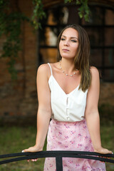 Portrait of a girl who pensively looks to the side, on a summer day against the background of an old brick window