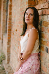 Portrait of a girl in a dress, against the background of an old, red brick wall.
