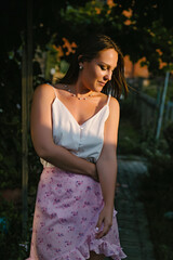 The girl in the garden against the background of the path and leaves of grapes posing in the sun.