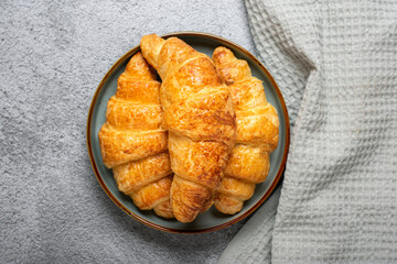Fresh french croissants with chocolate on plate, napkin on gray granite background Continental morning breakfast Top view Flat lay