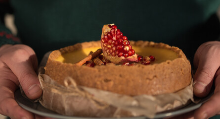 Homemade cheesecake with Christmas spices in woman hands. Delicious cheese cake with berries, healthy organic summer dessert pie.