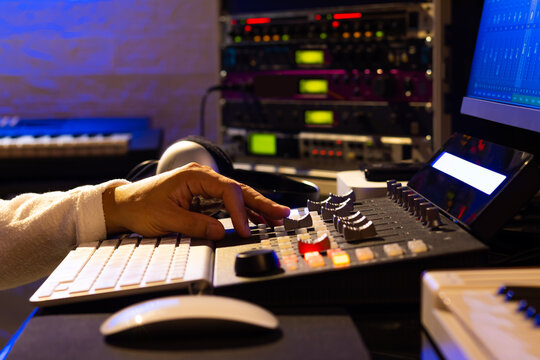 Sound engineer hands adjusting volume on digital audio control surface for mixing audio tracks on computer. Post production, broadcasting, recording concept