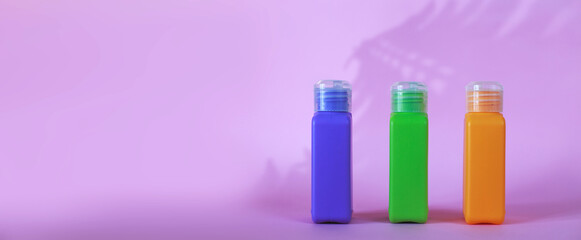 Isolated spa cosmetic products, multicolored tubes on a pink background. banner