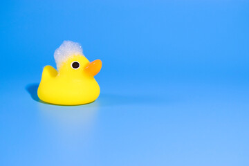 yellow duck for swimming with foam on a blue background