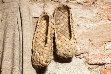 Vintage Russian bast shoes hang on brick wall