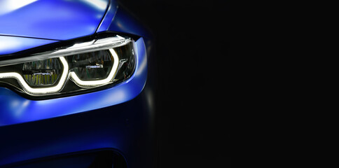 Close up detail blue modern car headlights with led technology on black background free space on right side for text.